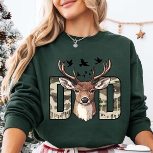 a woman wearing a green sweatshirt with a deer on it