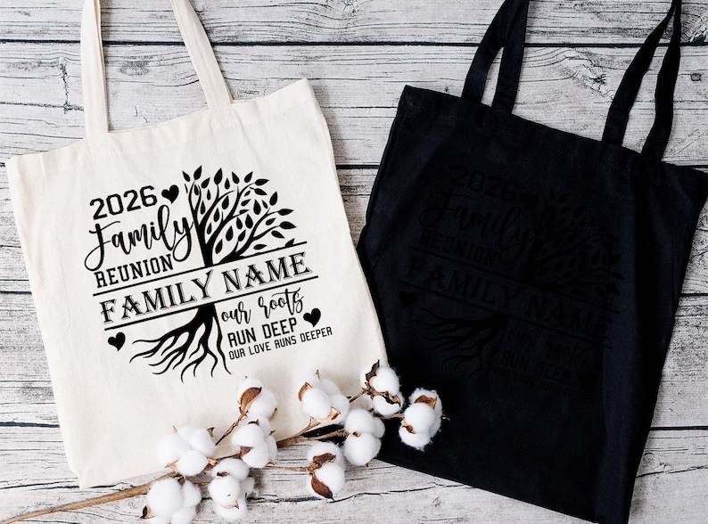 Two tote bags with a family tree design and text printed on them, placed on a wooden surface with cotton bolls in the foreground.