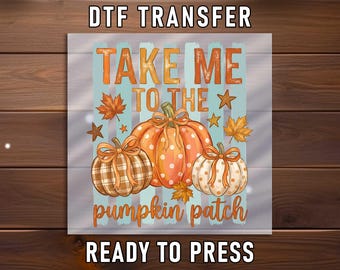 May include: A DTF transfer sheet featuring the text TAKE ME TO THE pumpkin patch READY TO PRESS. The design includes three pumpkins with bows, one with a plaid pattern and two with polka dots, surrounded by orange maple leaves and stars.
