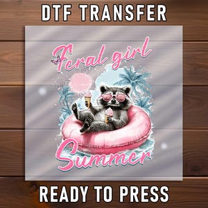 May include: DTF transfer featuring a raccoon wearing sunglasses and floating on a pink inflatable ring, holding ice cream cones. The words "Feral girl Summer" are in pink script. The words "READY TO PRESS" are at the bottom.