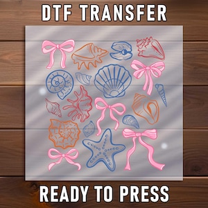 May include: DTF transfer sheet featuring a collection of seashells, starfish, and pink bows. The seashells are in orange and blue, with the text "DTF TRANSFER" and "READY TO PRESS" in white.