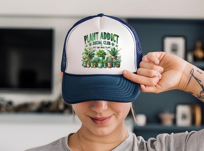 a woman holding up a trucker hat with plants on it
