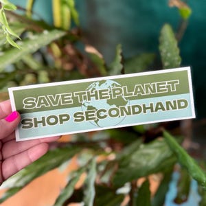 Pode incluir: Um adesivo verde e azul com um gráfico de um globo terrestre e o texto "SAVE THE PLANET SHOP SECONDHAND".
