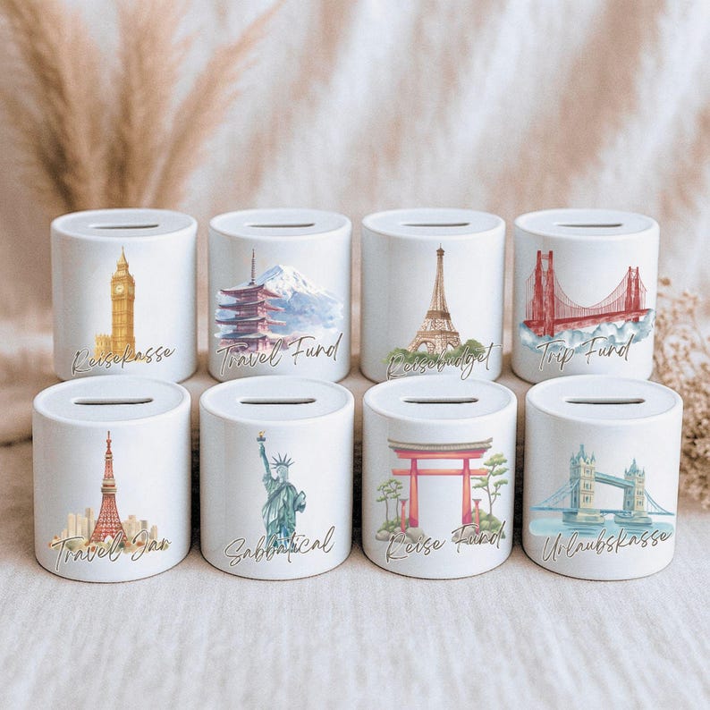 May include: Eight white ceramic money banks with travel-themed illustrations. Each bank features a different landmark, including the Eiffel Tower, the Statue of Liberty, and the Golden Gate Bridge. Text on the banks includes "Travel Fund" and "Sabbatical".