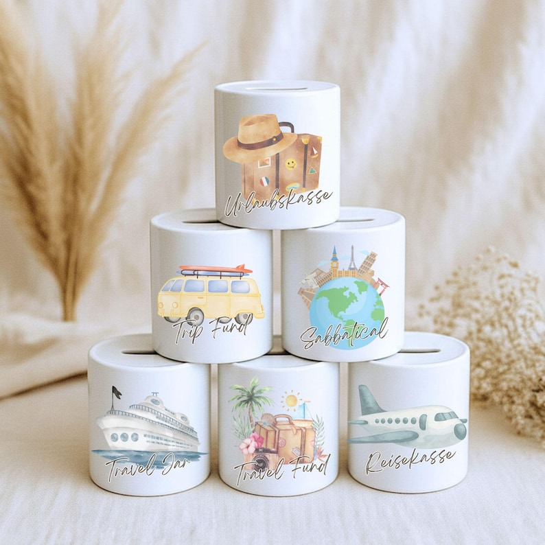 May include: White ceramic travel-themed piggy banks with various illustrations. Designs include a suitcase, a yellow van with a surfboard, a globe with landmarks, a cruise ship, a suitcase with tropical flowers, and an airplane. Each bank has a slot for coins.