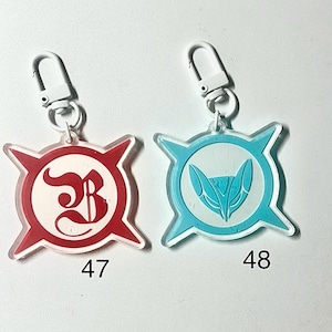 May include: Two keychains with clear plastic bodies and silver-colored clasps. One keychain has a red and white design with the number 47. The other has a blue and white design with the number 48. Both keychains have a starburst shape.