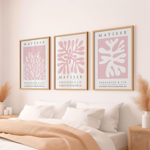 May include: Three framed art prints with pink backgrounds and white abstract floral designs. The prints are titled "MATISSE" and include the text "BERGGRUEN & CIE" and the date "27 Janvier au 28 Mars 1953".