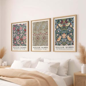 May include: Three framed prints of William Morris floral designs. The prints are in a minimalist style with a white background and a simple black font. The text on the prints reads "William Morris" and the name of the institution where the print is housed. The prints are arranged in a row on a white wall.