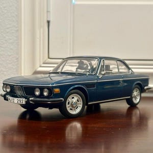 Puede incluir: Un coche modelo BMW 2002 azul de la década de 1970 con una matrícula negra que dice "M-YZ 292".