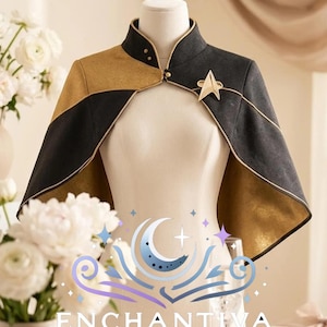 Könnte beinhalten: Ein schwarzes und goldenes Cape mit hohem Kragen, goldener Paspelierung und einem goldenen sternförmigen Emblem auf der linken Seite. Das Kleidungsstück wird auf einer Schneiderpuppe präsentiert und zeigt den Text ENCHANTIVA By A&M Bridal.