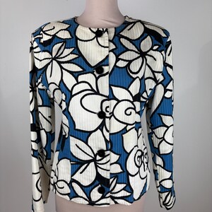 Puede incluir: Una chaqueta de botones con estampado floral blanco y azul y mangas largas.