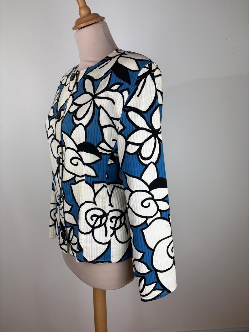 Puede incluir: Una chaqueta con estampado floral azul y blanco con cierre de bot&oacute;n. La chaqueta tiene mangas largas y una silueta ajustada.