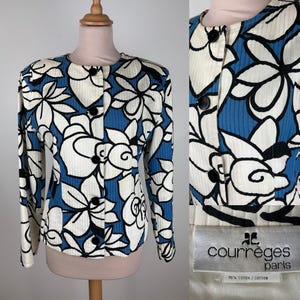 Puede incluir: Una chaqueta azul y blanca con estampado de flores, cuello redondo y mangas largas. La chaqueta tiene cierre de botones y lleva una etiqueta negra con el texto "Courr&egrave;ges Paris" y "100% algod&oacute;n / coton".