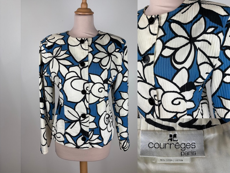 Puede incluir: Una chaqueta azul y blanca con estampado de flores, cuello redondo y mangas largas. La chaqueta tiene cierre de botones y lleva una etiqueta negra con el texto "Courr&egrave;ges Paris" y "100% algod&oacute;n / coton".