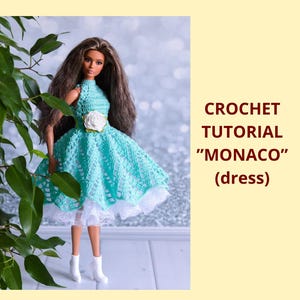Könnte beinhalten: Eine Puppe trägt ein türkisfarbenes Häkelkleid mit weißer Spitzenborte und einer weißen Blumenverzierung. Das Kleid ist Teil eines Häkel-Tutorials mit der Bezeichnung "MONACO" (Kleid). Die Puppe hat lange braune Haare und trägt weiße Stiefel.