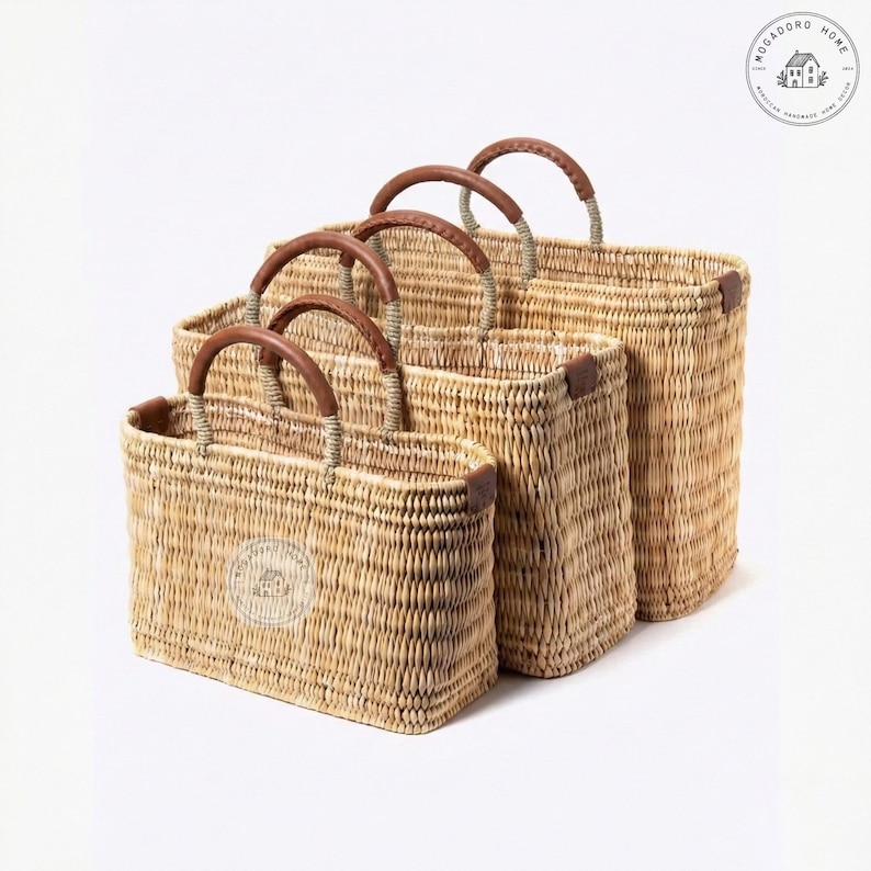 Peut inclure: Quatre paniers rectangulaires tress&eacute;s de diff&eacute;rentes tailles. Chaque panier a une poign&eacute;e en cuir marron et des coins renforc&eacute;s. Les paniers sont faits d'un mat&eacute;riau beige clair et sont dispos&eacute;s du plus petit au plus grand.