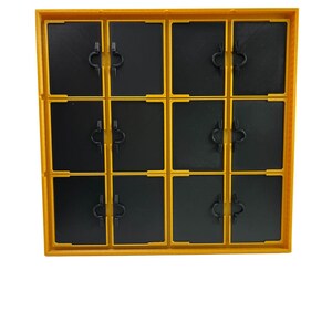 May include: A yellow and black plastic storage container with a grid of twelve compartments. Each compartment has a black door with a small, black handle. The container is designed for organizing small items.
