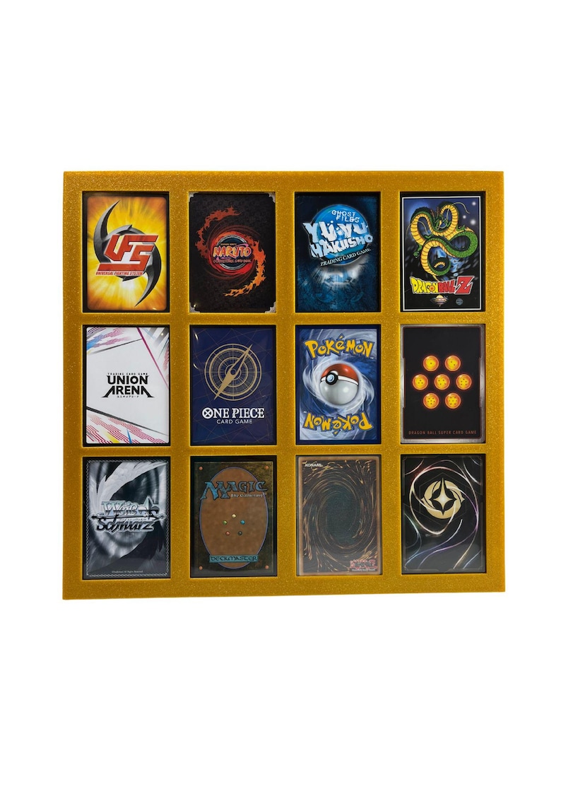 May include: A gold-colored display case holding twelve trading cards. The cards feature various designs and logos, including "Naruto," "Pokemon," and "Dragon Ball Z." The case has a rectangular shape with a gold border, showcasing the cards in a grid arrangement.