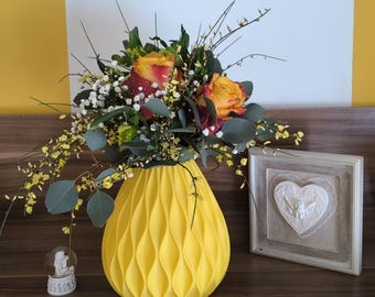 May include: A yellow ceramic vase with a pleated design holds a bouquet of orange and red roses with white baby's breath.