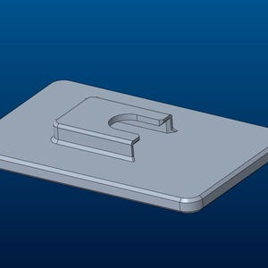 May include: A light gray rectangular plate featuring a central raised section with a U-shaped cutout. The object has rounded corners and a smooth, uniform surface finish, presented in a three-dimensional digital rendering against a blue background.