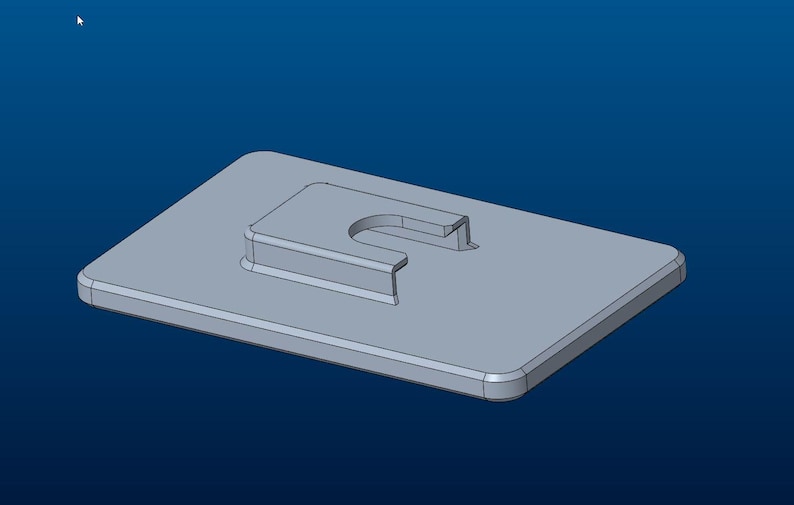 May include: A light gray rectangular plate featuring a central raised section with a U-shaped cutout. The object has rounded corners and a smooth, uniform surface finish, presented in a three-dimensional digital rendering against a blue background.