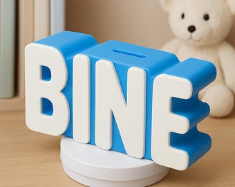May include: A blue and white piggy bank in the shape of the word "BINE". The letters are white with a blue outline. The piggy bank sits on a white circular base. A slot is visible on the top. A white teddy bear is in the background.