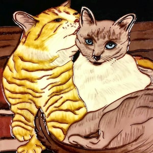 May include: A ceramic tile featuring a close-up of two cats. The cat on the left is orange and white with stripes. The cat on the right is a Siamese with blue eyes. The cats are cuddling together.