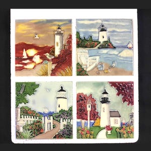 May include: Set of four ceramic tiles featuring colourful illustrations of lighthouses in different settings. Each tile depicts a lighthouse with a white tower and red roof, surrounded by various elements like seascapes, gardens, and beach scenes.