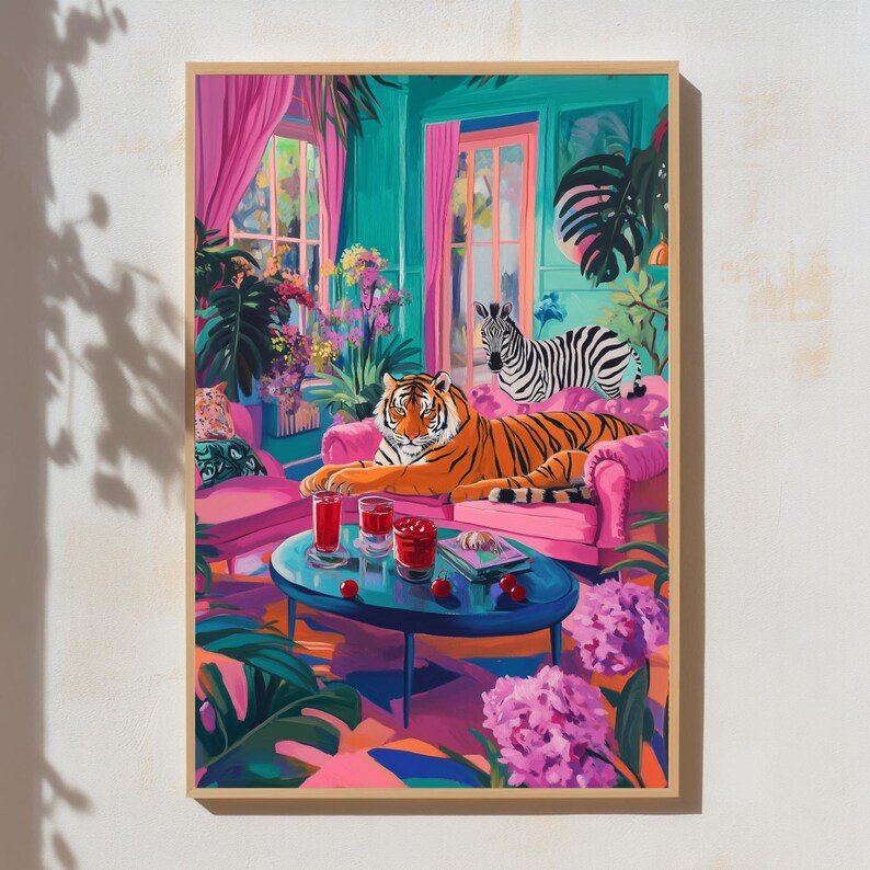 May include: A framed art print depicts a vibrant interior scene. A tiger lounges on a pink sofa, with a zebra nearby. The room features pink curtains, a blue table with drinks, and lush plants. The artwork is rich in color and detail.