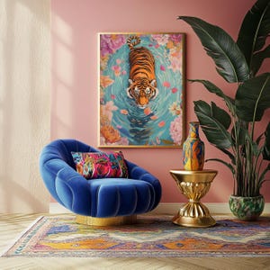 Pode incluir: Uma obra de arte emoldurada retrata um tigre em um lago cercado por flores. Uma cadeira de veludo azul com base dourada est&aacute; em frente &agrave; obra de arte. Uma almofada colorida repousa sobre a cadeira. Uma mesa lateral dourada sustenta um vaso decorativo.