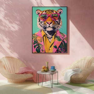 Op de afbeelding: Een ingelijste kunstdruk met een tijger met een roze zonnebril en een roze bloemenblazer over een gele blouse. Het gezicht van de tijger is gedetailleerd met zwarte strepen en een roze neus. De achtergrond is lichtblauwgroen.