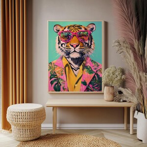 Op de afbeelding: Een ingelijste kunstdruk met een tijger met een roze zonnebril, een geel overhemd en een roze bloemenblazer. De tijger staat tegen een turquoise achtergrond. Het kunstwerk wordt tentoongesteld op een licht houten bankje.