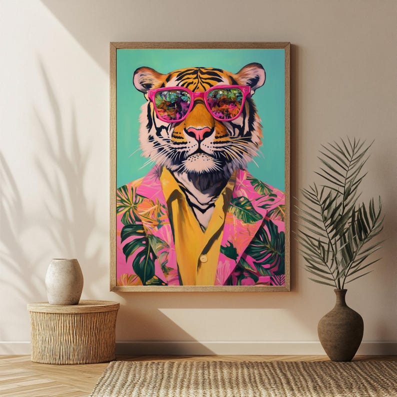 Op de afbeelding: Een ingelijste kunstdruk met een tijger met een roze zonnebril en een roze blazer met bloemenprint over een geel overhemd. De tijger heeft zwarte strepen en een roze neus, tegen een turquoise achtergrond.