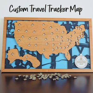 May include: Wooden travel tracker map of the United States with a light brown finish. The map is framed and features cutouts for state markers. The background is blue with black silhouettes of runners. The text "Custom Travel Tracker Map" is at the top.