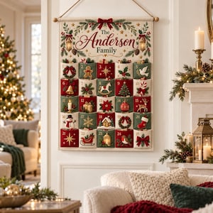 Pode incluir: Um calendário do advento de tecido para pendurar na parede com o texto The Anderson Family no topo. Possui vinte e cinco bolsos numerados em vermelho e verde, cada um decorado com motivos natalinos bordados como um boneco de neve e estrela.