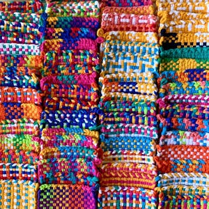 May include: A collection of colorful woven pot holders in various patterns and colors, including red, blue, green, yellow, orange, and white.