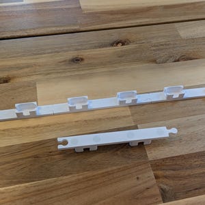 May include: Two white plastic pieces with multiple slots. The larger piece has eight slots and the smaller piece has five slots.