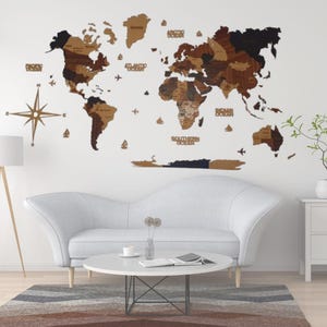 Puede incluir: Un mapa del mundo de madera con fondo blanco. El mapa está hecho de piezas individuales de madera que se organizan para formar los continentes. El mapa está montado en una pared blanca sobre un sofá blanco y una mesa de café blanca. El mapa incluye los nombres de los océanos, "Océano Ártico", "Océano Atlántico", "Océano Índico" y "Océano Austral".