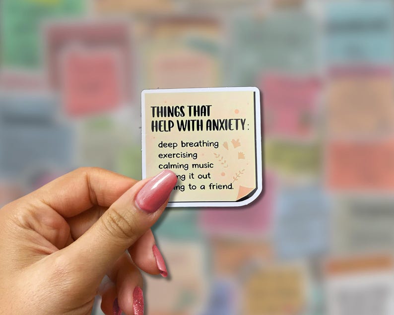 May include: A square sticker with the text "THINGS THAT HELP WITH ANXIETY:" and a list of coping mechanisms. The sticker is held by a hand with pink nail polish, with a colorful background of other stickers.