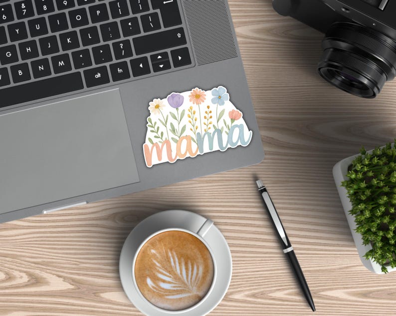 May include: A sticker with a floral design and the word "mama" in pastel colors. The sticker is on a laptop.