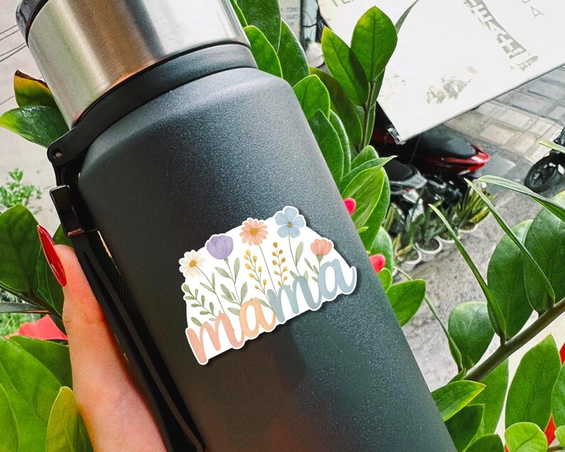 May include: A black stainless steel water bottle with a floral sticker that says "mama" in a light blue, pink, and white font.