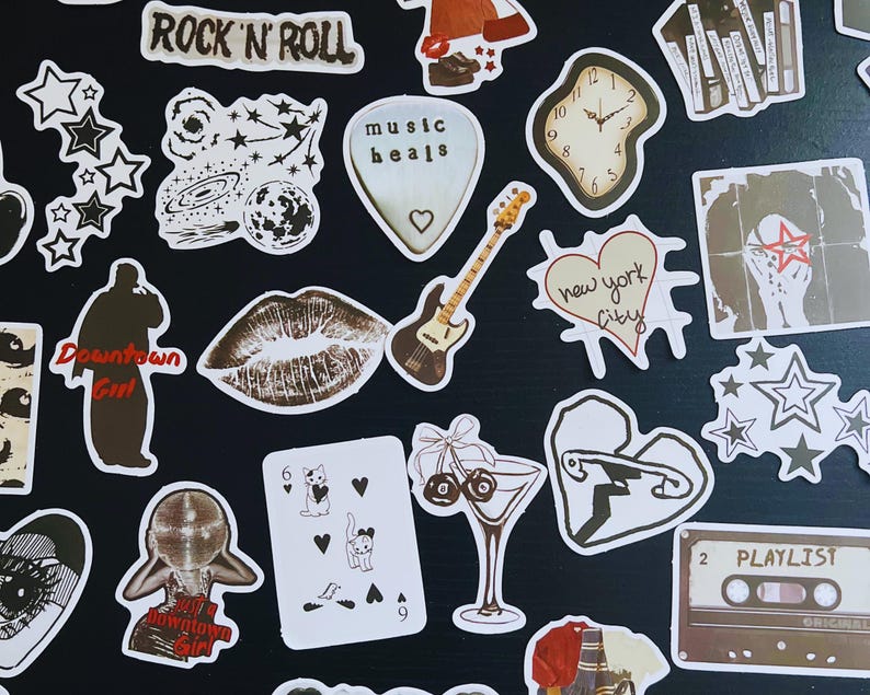 May include: A collection of assorted stickers with a rock and roll theme. Designs include a guitar, lips, a clock, stars, and the words "Rock 'N' Roll", "music heals", "Downtown Girl", and "New York City".