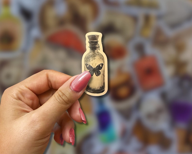 May include: A sticker featuring a vintage-style bottle with a butterfly illustration. The bottle is beige with a dark cap and a black butterfly in the center. The sticker has a slightly blurred background with other similar stickers.