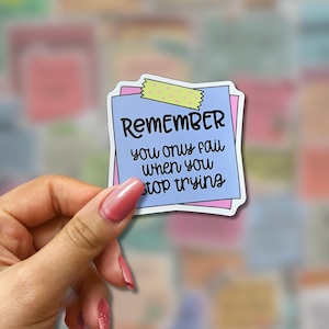 May include: A sticker with the text "REMEMBER you only fail when you stop trying" on a blue sticky note with a pink border, held by a hand. The sticker is decorated with a piece of yellow and green washi tape.