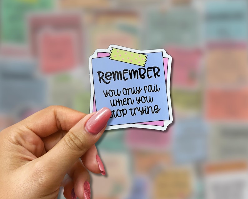 May include: A sticker with the text "REMEMBER you only fail when you stop trying" on a blue sticky note with a pink border, held by a hand. The sticker is decorated with a piece of yellow and green washi tape.