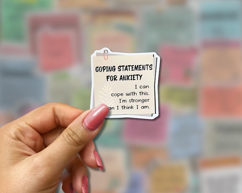May include: A sticker with the text "GOPING STATEMENTS FOR ANXIETY". The sticker has a light beige background with a paperclip at the top. The text reads "I can cope with this. I'm stronger than I think I am."