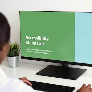 Può includere: Uno schermo di computer che mostra una presentazione intitolata "Standard di accessibilità" con uno sfondo verde e blu. Il testo sullo schermo recita "Comprendere la legge sull'accessibilità per gli Ontariani con disabilità."