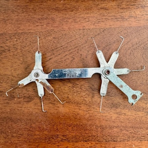 May include: A vintage Companion P-4075 feeler gauge tool made in the USA. The tool is silver-colored with multiple arms and measuring tips. The tool is designed for measuring gaps and clearances.