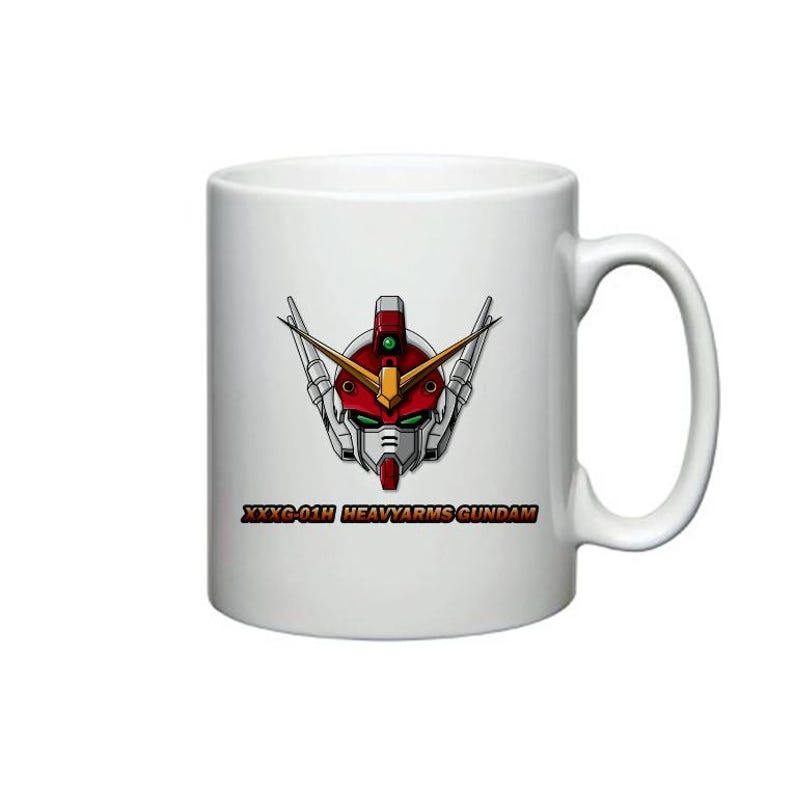 Pu&ograve; includere: Tazza in ceramica bianca con un'immagine di una testa di robot rosso, bianco e grigio. Il testo "XXXG-01H HEAVYARMS GUNDAM" &egrave; stampato sotto l'immagine.
