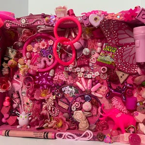 Könnte beinhalten: Eine rosa Schattenbox gefüllt mit verschiedenen rosa Objekten, darunter ein Flamingo, ein Buntstift, ein Ballonhund und die Worte "THINK PINK". Die Box ist mit Blumen, Schleifen und anderen kleinen Schmuckstücken dekoriert.